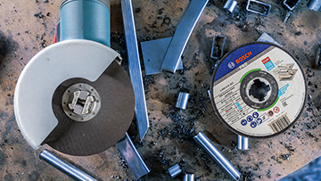A Bosch Professional angle grinder rests on a workbench surrounded by metal scraps and a grinding disc.