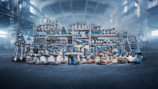 A wide array of blue and gray power tools displayed on shelves in an industrial setting, with dim lighting.