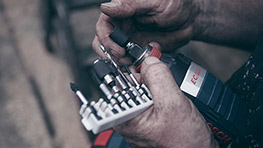 A person holds a Bosch Professional electric screwdriver with various bits nearby.