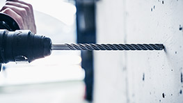 A Bosch Professional drill is drilling into a concrete wall, with a focus on the bit.