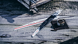 Two Bosch Professional saw blades and a nut on a wooden surface with measurements.