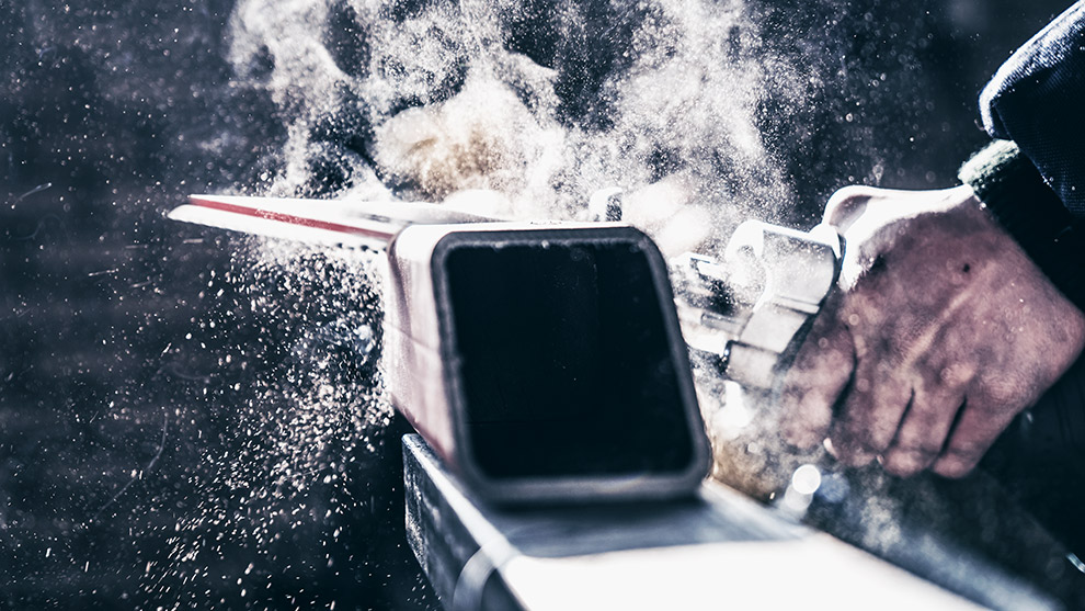 A Bosch Professional planer in action, producing wood shavings and dust in a workshop.