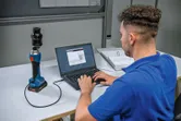 A person connects a cordless hydraulic punching tool to a laptop at a desk.