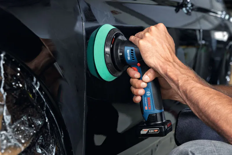 A person uses a cordless polisher on a car door.