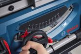 A person adjusts the angle gauge on a blue table saw.