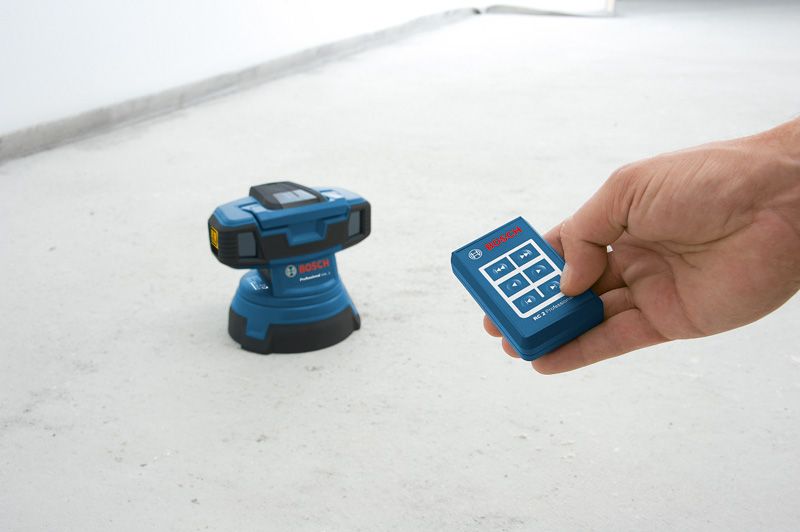 Person operating a remote control for a laser leveling tool on a concrete floor.