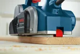 Electric planer smoothing the surface of a wooden board.