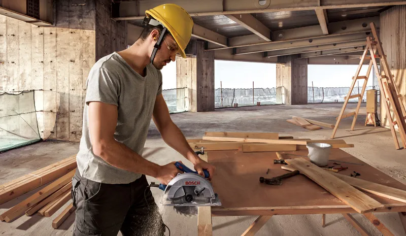 Worker sawing wooden board.