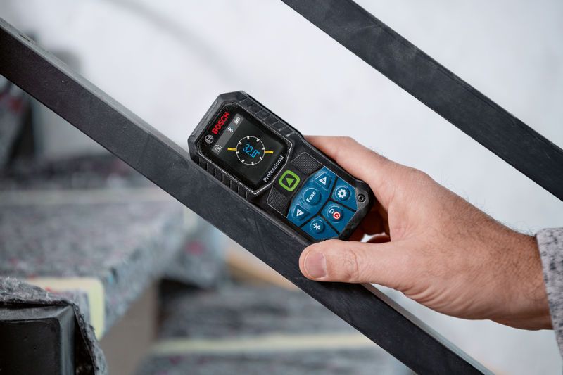 Person using a laser measure to check the angle of a metal railing.