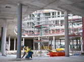 A person wearing safety equipment uses a laser measure to check a column alignment on site.