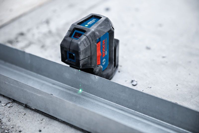Laser leveling tool projects a green line onto a metal track for alignment.
