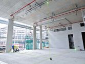 A person wearing safety equipment marks the floor using a laser leveling tool projecting green lines.