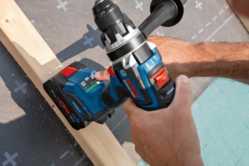 Person using a cordless drill to fasten a screw into a wooden beam.