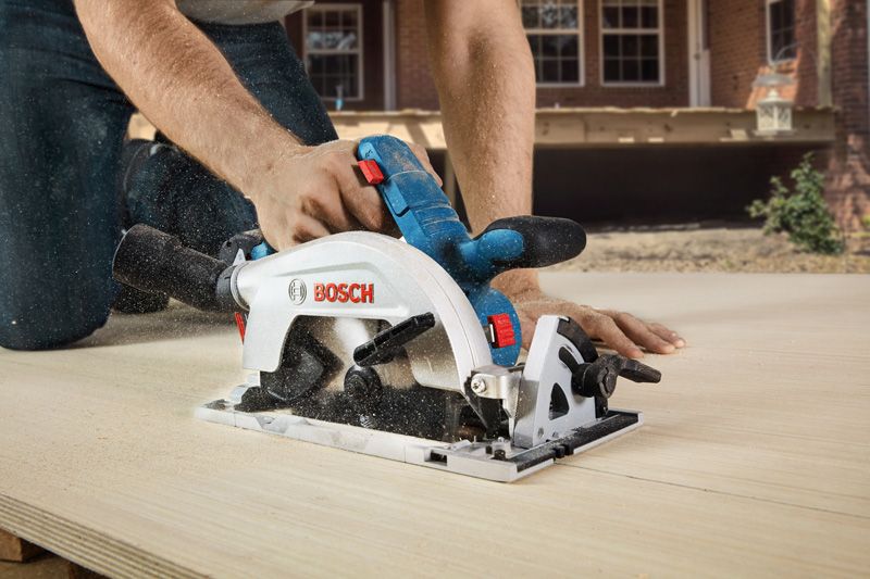 A person uses a circular saw to cut wood outdoors.