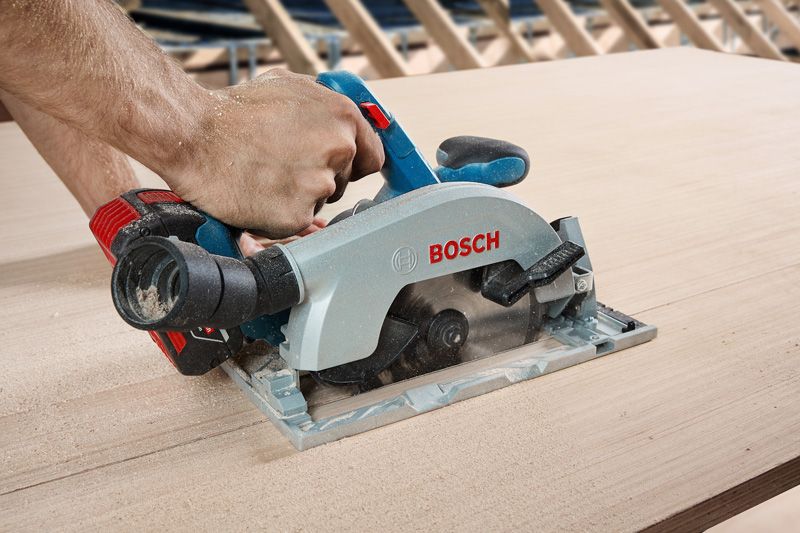 A person uses a circular saw to cut a sheet of wood.