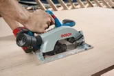 A person uses a circular saw to cut a sheet of wood.