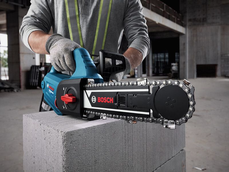 A person wearing safety equipment uses an AAC block cutter on a concrete block.