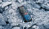 Laser measure device resting on broken concrete debris.