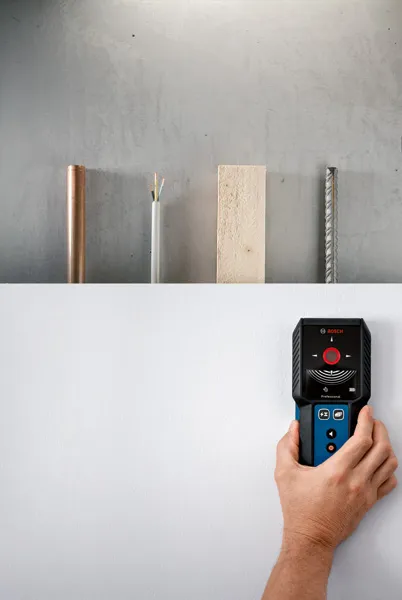 Person using a detector device to locate objects behind a wall.