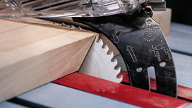 Circular saw blade cutting through a wooden board at an angled position.