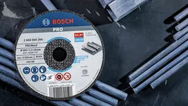 Grinding disc placed on a dark surface with scattered metal rods.