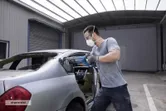 Person wearing safety equipment uses a reciprocating saw to cut a car’s rear window frame.