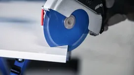 Circular saw cutting a white tile sheet in a workshop.