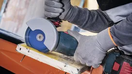 Person wearing safety equipment cuts wood with a circular saw.