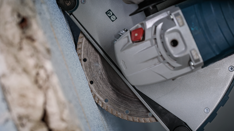 Cutting tool with a diamond blade makes a straight groove in a concrete wall.