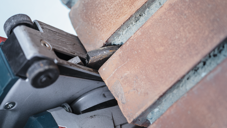 Κόφτης πλακών σκυροδέματος που δημιουργεί μια ακριβή αυλάκωση σε μια επιφάνεια από τούβλα.