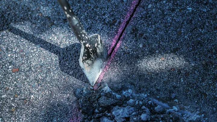 Σμίλη που σπάει σκυρόδεμα κατά μήκος μιας σημαδεμένης γραμμής.