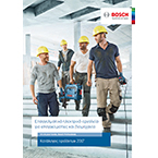 Τέσσερις εργάτες με κράνη περπατούν σε εργοτάξιο, κρατώντας εργαλεία.