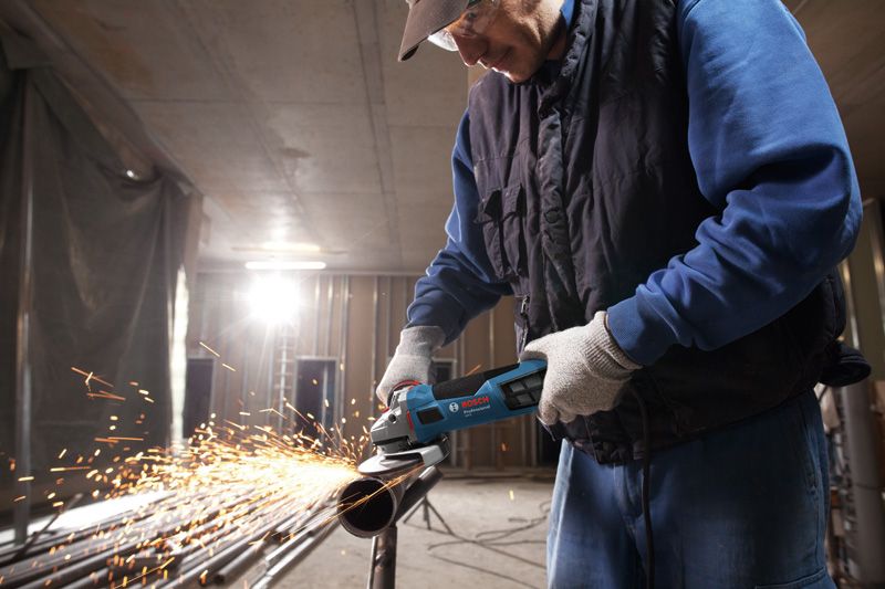 Osoba koja nosi zaštitnu opremu melje metalnu cijev, pri čemu nastaju iskre.