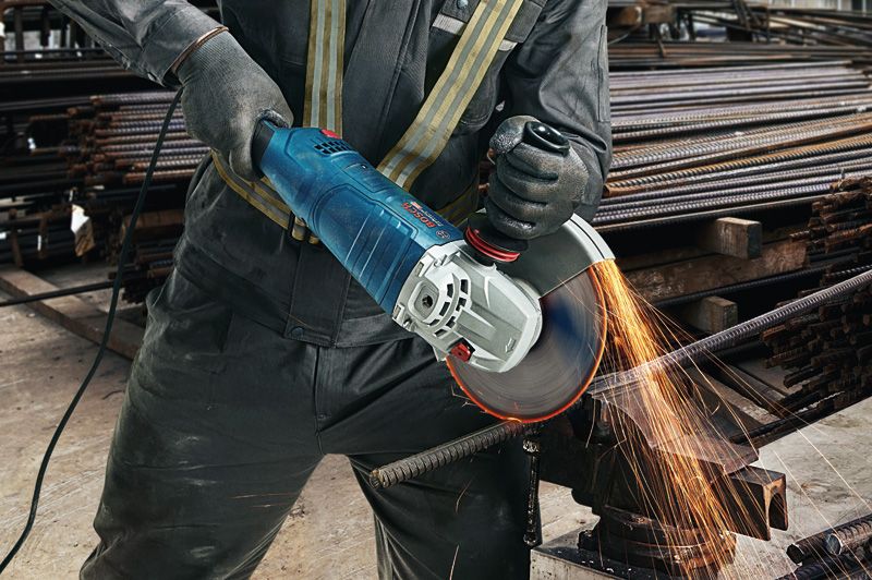 Osoba u zaštitnoj opremi reže metalnu armaturu kutnom brusilicom, uz iskre.