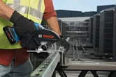 Osoba koja nosi zaštitnu opremu reže metalni kanal bežičnom kružnom pilom.