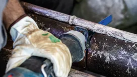 Osoba koja nosi zaštitnu opremu koristi recipročnu pilu za rezanje metalne cijevi.
