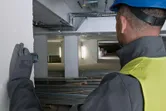 Osoba koja nosi zaštitnu opremu koristi laserski mjerač za provjeru udaljenosti na gradilištu.