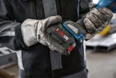 Osoba koja nosi zaštitnu opremu ugrađuje bateriju na bežični električni alat.