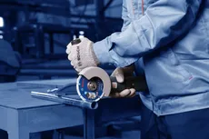 Osoba koja nosi zaštitnu opremu koristi kutnu brusilicu za rezanje metalne cijevi.