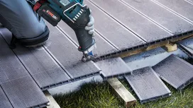 Osoba koja nosi zaštitnu opremu reže kompozitne podove električnim alatom.