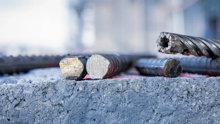 Vágott acélbetét és egy forgó fúrófej egy durva betonfelületen nyugszik.