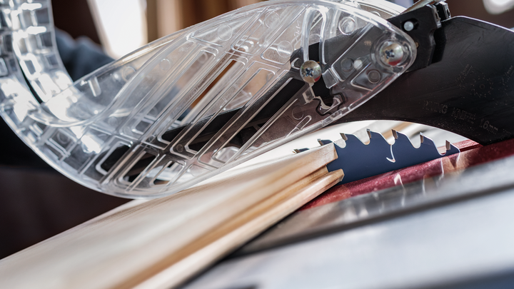 Körfűrész fa deszkát vág, védő pengevédővel a helyén.