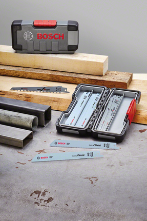 Saw blades in a storage case with metal pipes and wooden planks on a work surface.