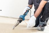 A person wearing safety equipment uses a heat gun to weld flooring.