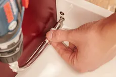 Person using a flexible shaft attachment to drive a screw into a tight space.
