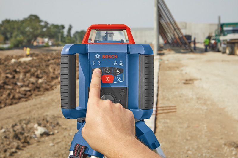 Person operating a laser leveling tool at a construction site.