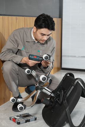Person wearing safety equipment assembles an office chair using a cordless drill.