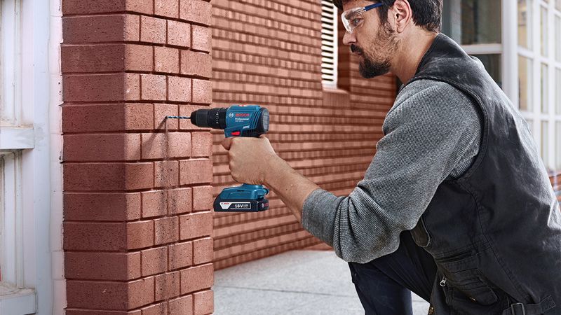 Man drilling into brick wall.