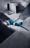 A person wearing safety equipment cuts a stone slab with an angle grinder.