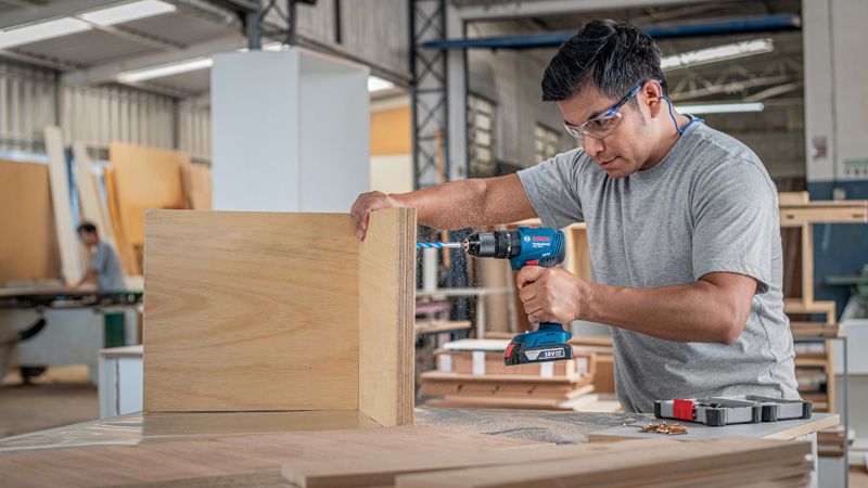 Man drilling wooden boards.